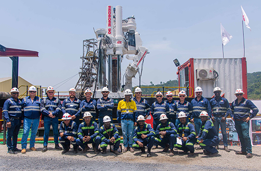Un numeroso grupo de empleados de Redpath Africa delante de una perforadora elevada Redbore 90.